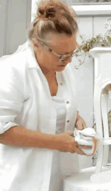 a woman in a white shirt and glasses is cleaning a white table .