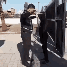 a man and a woman are standing next to each other on a sidewalk in front of a gate .