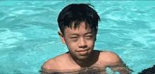 a young boy is swimming in a pool and making a funny face .