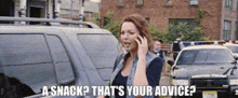 a woman is talking on a cell phone while standing in front of a police car and a building .