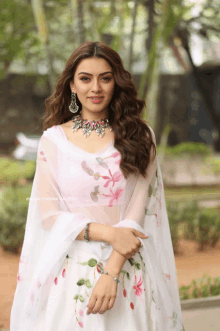 a woman wearing a white dress with a floral embroidery on it