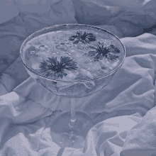 a glass filled with ice and flowers on a bed