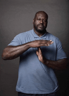 a man in a blue shirt is making a stop gesture