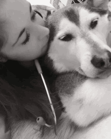 a woman kissing a husky dog with a stethoscope