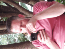 a man in a pink shirt is looking at a cell phone