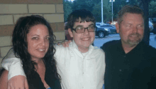 a man and a woman are posing for a photo with a boy wearing glasses