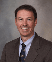 a man in a suit and tie smiles for a picture