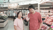 a man and a woman are standing in a grocery store with a sign above them that says fresh market