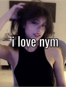 a girl in a black tank top is sitting in a chair with her hair in her hand and says `` i love nym '' .