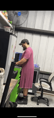 a man in a pink dress is standing in a garage .