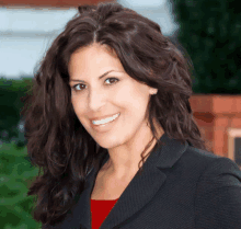 a woman wearing a black jacket and red shirt smiles for the camera