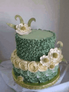 a green and white cake with flowers on it is on a table .