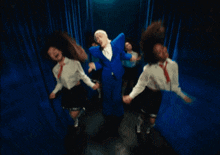 a man in a blue suit is dancing with a group of women