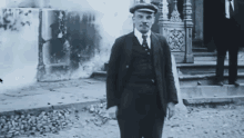 a black and white photo of a man wearing a suit and hat