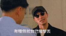 a man wearing sunglasses and a baseball cap is talking to another man .