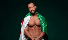 a shirtless man with a green and white flag draped over his shoulders