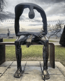 a statue of a person sitting on a bench with a tear coming out of his head .