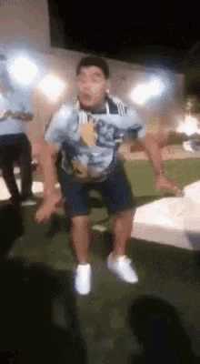 a man in a blue shirt and shorts is jumping in the air while wearing white sneakers