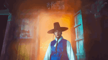 a man wearing a hat and a blue vest is standing in front of a door that has chinese writing on it