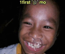 a young boy with a pacifier in his nose is smiling and looking at the camera .