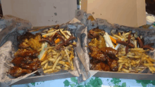 two boxes filled with chicken wings and french fries are sitting on a table