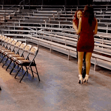 a woman in a red dress is standing next to another woman in a red dress in a stadium .