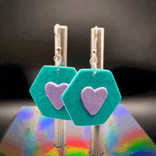 a pair of turquoise earrings with purple hearts on them