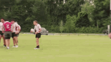 a group of people are playing a game of rugby on a field . one of the players has the number 2 on his jersey .