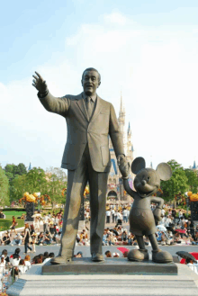 a statue of walt disney and mickey mouse in front of the castle