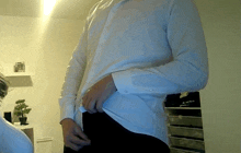 a man wearing a white shirt and black pants is taking off his shirt