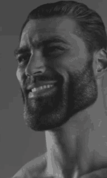 a black and white photo of a man with a beard smiling and looking at the camera .