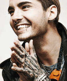 a man with a tattoo on his hand is smiling and wearing earrings