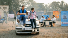 a man and a woman are sitting on a car with a license plate that says ch 02 uh 340