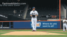 a mets pitcher stands on the mound in front of a sign that says " where do you want to sit "