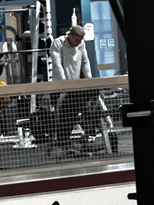 a man in a gym behind a fence with a sign on the wall that says ' no smoking '