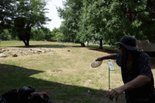 a man throwing a frisbee in a park with a sign that says ' a few steps ' on it