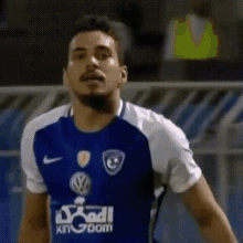 a soccer player wearing a blue and white jersey with the word kingdom on it is standing on a field .