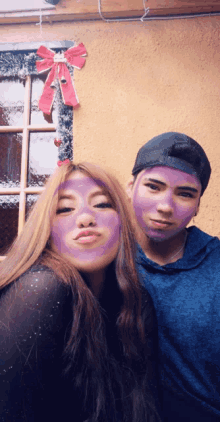 a man and a woman are posing for a picture with purple paint on their faces