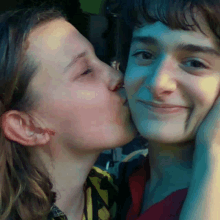 a girl kisses a boy on the cheek in a close up