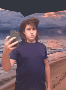 a young man taking a selfie on the beach with his phone