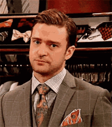 a man in a suit and tie is standing in front of a display of ties and bow ties .