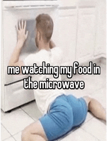 a man is kneeling on the floor in front of a microwave oven .