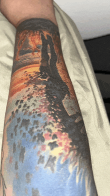 a person with a tattoo on their arm that looks like a painting of a beach