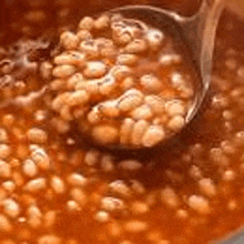 a close up of a spoon in a pot of soup with beans .