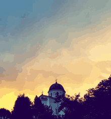 a church with a dome and a cross on top of it at sunset