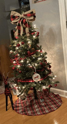 a christmas tree with a plaid skirt and a large bow on top