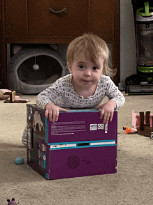 a little girl is playing with a box that says ' barbie ' on the back