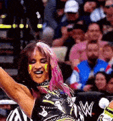 a woman with pink hair is wrestling in front of a crowd of people .