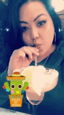 a woman is drinking a margarita through a straw with a picture of a cactus on it .