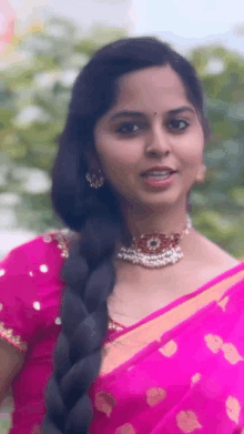 a woman with long hair is wearing a pink saree and a braid .